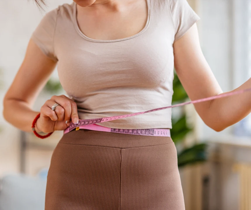 tummy tuck recovery: woman measuring waist